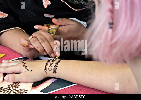 Artista applicando henna tattoo sulle mani delle donne. Mehndi è indiana tradizionale arte decorativa. Close-up Foto Stock