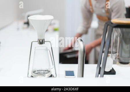 Processo di preparazione di caffè nero in chemex versare il caffè in luminoso moderno cafe'. Modi alternativi per preparare il caffè. Foto Stock
