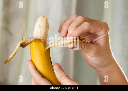 Mani peeling Giallo maturo banana, close up Foto Stock