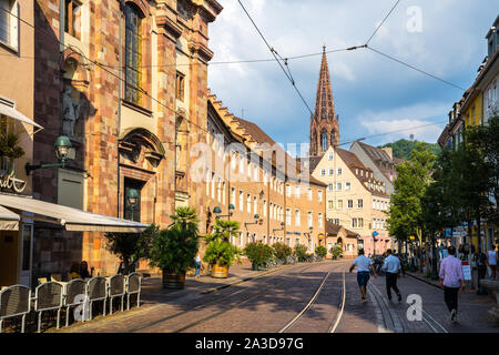 Freiburg im Breisgau, 30 agosto 2019, la gente camminare al fianco di rotaie del tram su strada di ciottoli nel centro storico con vista dell antica Foto Stock