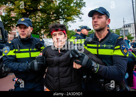 Un attivista XR si trova in stato di detenzione durante la protesta.per 2 settimane, estinzione della ribellione e movimenti alleati si riuniranno nelle principali città di tutto il mondo e continuano a ribellarsi contro i governi mondiali per la loro inazione penale sul clima e crisi ecologica. XR attivisti del clima di Amsterdam sono in corso per organizzare una larga scala di blocco della durata di più giorni sul Museumbrug, di fronte al Rijksmuseum. Dal mattino presto, centinaia di attivisti XR ha dimostrato fino al ponte, dove vi era un visibile la presenza della polizia. Il gruppo di ambiente estinzione della ribellione vuole l'olandese Foto Stock