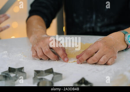 I ragazzi di Natale cottura gingerbread cookie nella cucina della casa sul giorno d'inverno. Close-up bambino le mani preparare i cookie utilizzando cookie cutter. Per la cottura Foto Stock