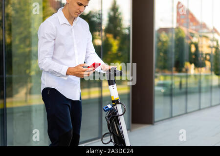 Giovani e casual uomo d affari di equitazione scooter elettrico in città Foto Stock