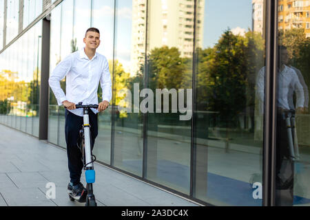 Giovani e casual uomo d affari di equitazione scooter elettrico in città Foto Stock