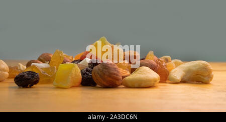Tutti frutti. Mix di frutta secca (uva passa, cedro, mango) e dadi (mandorle, nocciole) sulla luce di legno superficie lucidata Foto Stock