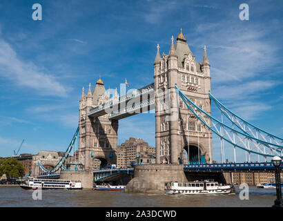 Barche sul fiume Tamigi passando sotto il Tower Bridge di Londra, Regno Unito Foto Stock