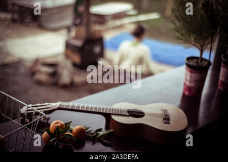 Chitarra acustica pone sul tavolo con freschi frutti raccolti sopra il posto del fuoco Foto Stock