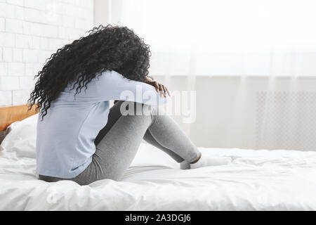 Vista posteriore della lonely giovane donna seduta sul letto Foto Stock