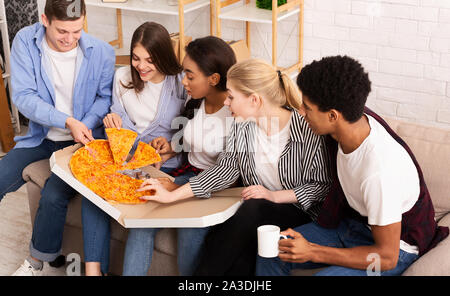 Happy amici prendendo fette di pizza calda dalla scatola di cartone Foto Stock