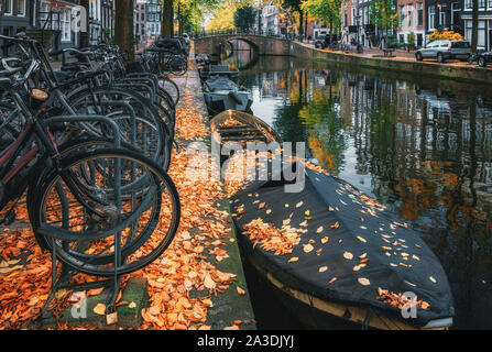 Le biciclette parcheggiate lungo un canale di Amsterdam in autunno i colori nei Paesi Bassi Foto Stock