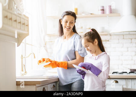 Bambina contribuendo a sua madre Lavaggio Piatti Foto Stock