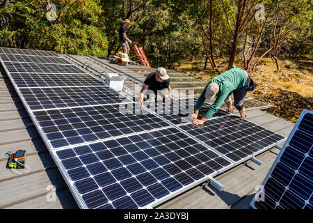 Lavoratori installare pannelli solari fotovoltaici sul tetto dei proprietari di abitazione in British Columbia, Canada. Foto Stock