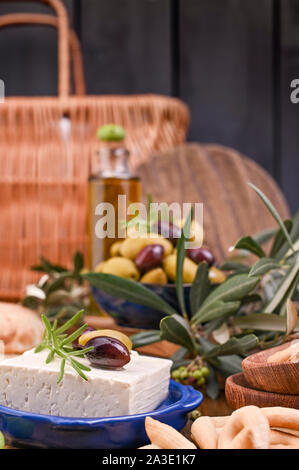 Formaggio greco feta con timo e olive, il fuoco selettivo. Pane e giovani Olive Branch sulla scheda di oliva su uno sfondo di legno vecchio. Vista aerea Foto Stock