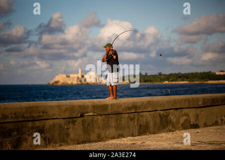 Un uomo pesci in Havana Malecon durante il tramonto. Foto Stock