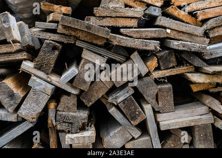 Piegate il vecchio legno marrone e grigio di tavole in una segheria. Impilate le schede ontano come texture. Foto Stock