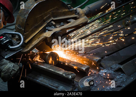 La formazione di scintille da sega circolare alla fabbrica di acciaio. Sezionatura di metallo vicino. Foto Stock