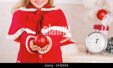 I bambini possono illuminare albero di natale creando i propri ornamenti. Pallina di natale decorazioni tradizionali. Top Natale che decora le idee per la stanza dei ragazzi. Bambino costume rosso tenere ornamento di Natale pallina. Foto Stock