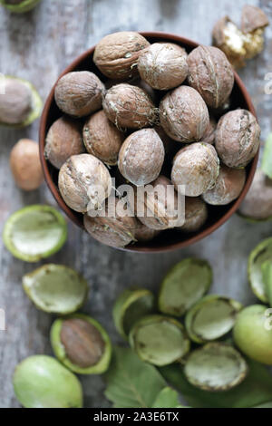 Noci di fresco in una ciotola. Il raccolto di noci. Noci pelate da gusci di verde. Le foglie di noce. Foto Stock