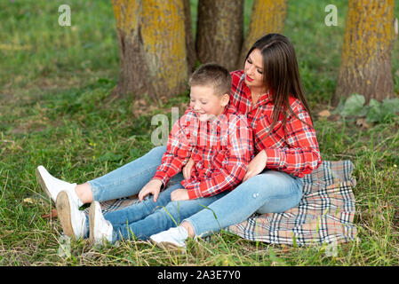 Madre e figlio seduti sul copriletto, parlare e sorridere. Foto Stock
