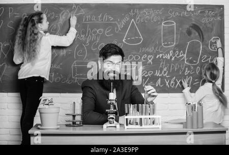 Studio per una prova. Insegnante di scuola e il gruppo di studio. Bambini piccoli e insegnante di scienze avente una sessione di studio. Effettuare lo studio e la sperimentazione nel campo della chimica. Foto Stock