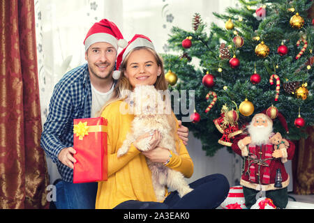 Sorridente Coppia matura indossando santa hat condivisione xmas presenta sotto albero di Natale Foto Stock