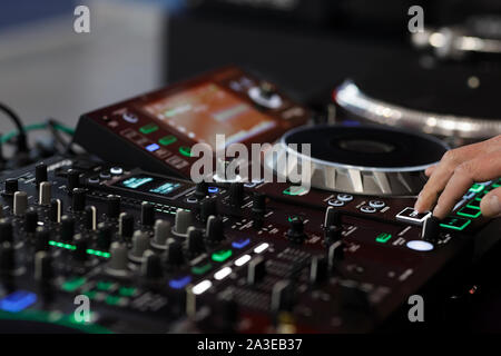 DJ utilizzando un mixer audio controller per riprodurre la musica. Messa a fuoco selettiva. Foto Stock