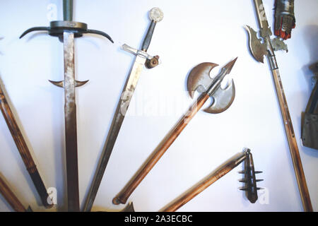 Molte diverse antica medievale spade e armi. Ferro metallico a due mani spade, macis scettro lancia lancia l'albero pike glaive gad su una parete ,histor Foto Stock