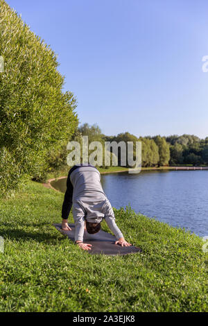 Ispirato uomo fare yoga asana nel parco della città. Centro Fitness all'aperto e di vita il concetto di equilibrio. Foto Stock