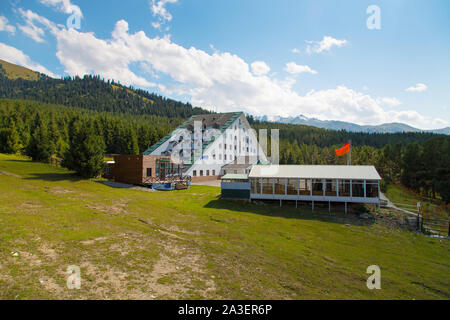 In Kirghizistan, Karakol ski resort - Agosto 22, 2019. Estate paesaggio di montagna in alta montagna. Alberi di alto fusto di alberi di Natale, ski-lift a sci Foto Stock