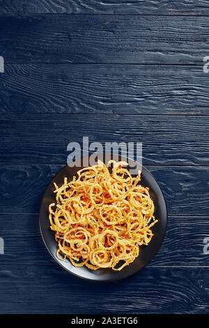 Vista aerea del francese cipolle fritte su una piastra nera su una tavola di legno, vista orizzontale dal di sopra, flatlay, spazio libero Foto Stock