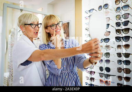 Bella giovane donna scegliendo nuovo paio di occhiali in negozio ottici. Ottica. Oftalmologia. Foto Stock