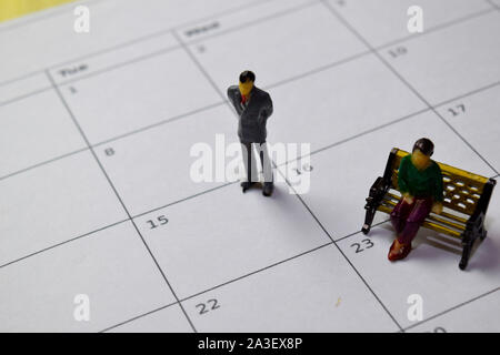 Miniatura persone in piedi e seduta essi pensando stipendio al XV sul calendario. Pianificazione, concetto di promemoria Foto Stock