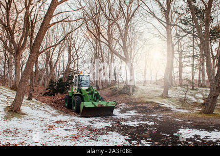 Trattore agricolo sotto albero sfrondato con coperte di neve in terra d'inverno. Hakodate, Hokkaido - Giappone Foto Stock