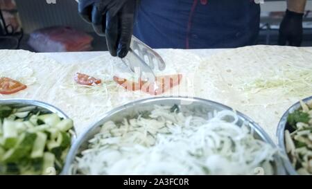 Il processo di preparazione di shawarma, il cuoco mette gli ingredienti. Close up Foto Stock