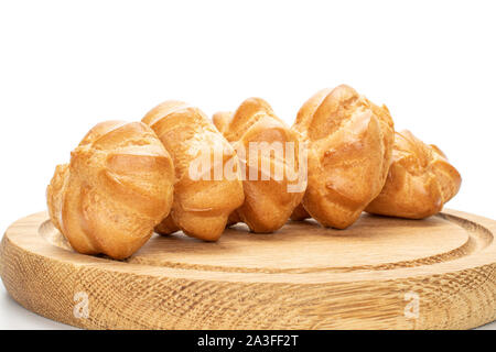 Il gruppo di cinque interi cotta profiterole dorata sulla piastra di bambù isolati su sfondo bianco Foto Stock