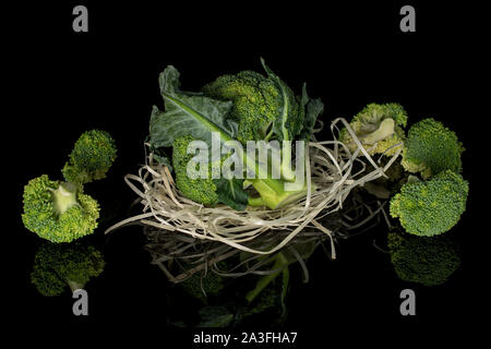 Sacco di intere fresche broccoli verdi nel nido di paglia isolato sul vetro nero Foto Stock