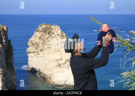 Beirut, Libano - 08 ottobre 2019. Un uomo orgogliosamente tiene il suo neonato dal bordo di Pigeon Rocks a Beirut Raouche Credito: amer ghazzal/Alamy Live News Foto Stock