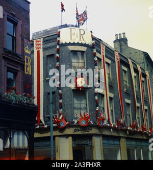 1953, storico, Regina della incoronazione, esterna di pub decorate con union jack flag, bunting e ER banner, Londra, Inghilterra, Regno Unito. L incoronazione della Regina Elisabetta II ha avuto luogo nel mese di giugno quando ella salì al trono all età di 25 dopo la morte di suo padre Re Giorgio VI l'anno precedente. Foto Stock