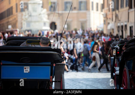 Un autista di un cavallo e di una carrozza in attesa di passeggeri in Piazza di Spagna. In lontananza si possono vedere i turisti che visitano Piazza di Spagna. Foto Stock