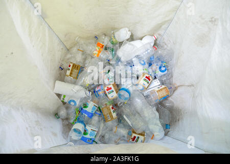 Bottiglie di plastica. Riciclare i rifiuti Nozione di gestione. La bottiglia di plastica nei rifiuti riciclabili. Urna bianca con plastica nella parte inferiore. Vista dall'alto. Bianco urna pulito per la plastica. Gli attivisti contro gli sprechi Foto Stock