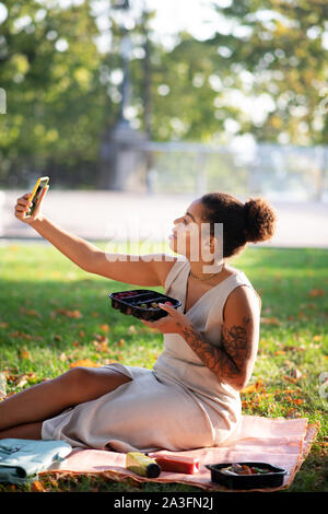 Donna fare selfie spendendo la pausa pranzo in posizione di parcheggio Foto Stock