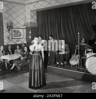 Degli anni Cinquanta, storico, all'interno di un ristorante a Nizza sulla Riviera Francese, una cantante femminile in piedi sulla pista da ballo esegue per i clienti da pranzo. Foto Stock