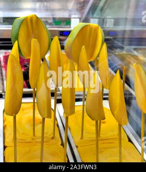 Mango aromatizzati gelato,decorate con mango fresco su bastoni Foto Stock