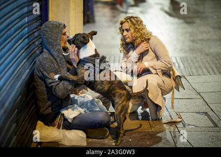 Cardiff Wales, un begger con un cane chat con una signora su una notte fuori Foto Stock