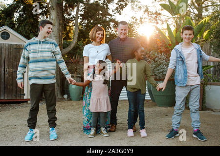 Felice di mixed-gara famiglia ridendo e tenendo le mani Foto Stock