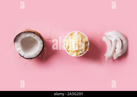 Disidratata, freschi e secchi scaglie di noce di cocco in ciotole di colore bianco su sfondo rosa. Vista da sopra. Foto Stock