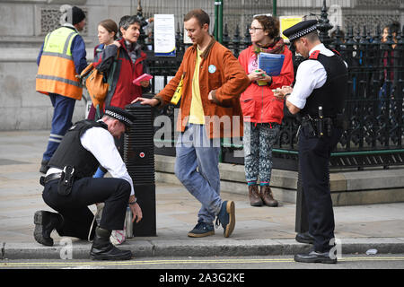 Una ribellione di estinzione (XR) protester ha il suo sacco cercato dalla polizia in piazza del Parlamento, Westminster, London, come il cambiamento climatico protesta continua in un secondo giorno. Foto Stock