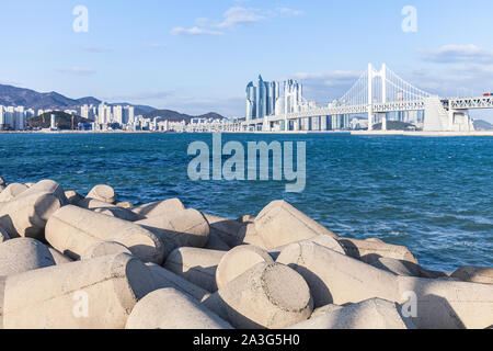 Corea del Sud. Paesaggio di Busan con calcestruzzo blocchi frangiflutti e la Gwangandaegyo o diamante ponte sullo sfondo Foto Stock