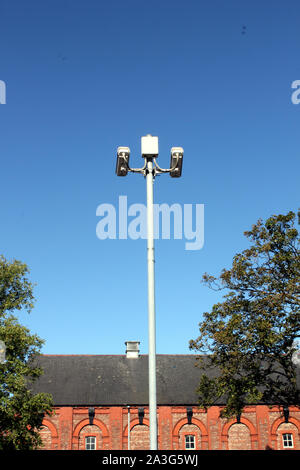 Vista verticale delle telecamere di sicurezza sul palo alto contro il profondo blu del cielo Foto Stock