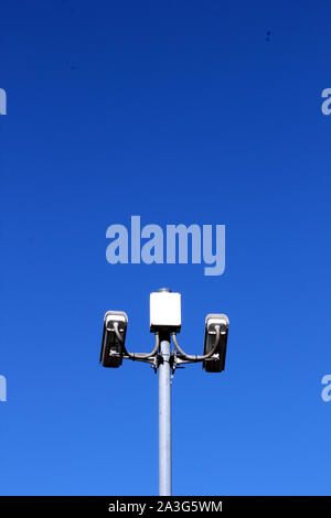 Vista verticale delle telecamere di sicurezza sul palo alto contro il profondo blu del cielo Foto Stock